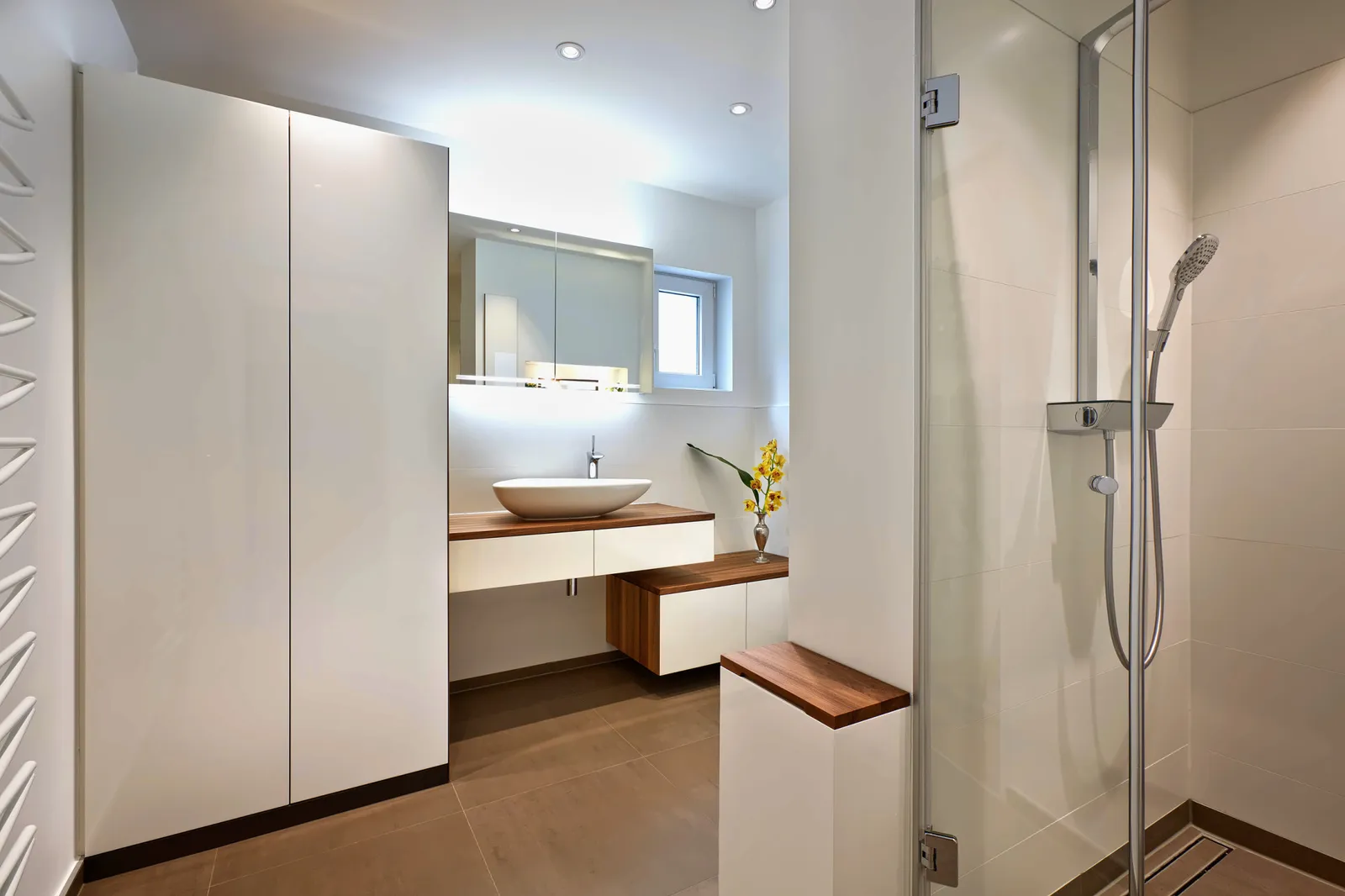 Hochschrank, Waschtisch und Sitzbank mit Nussbaum, Dusche mit Falttüren.
