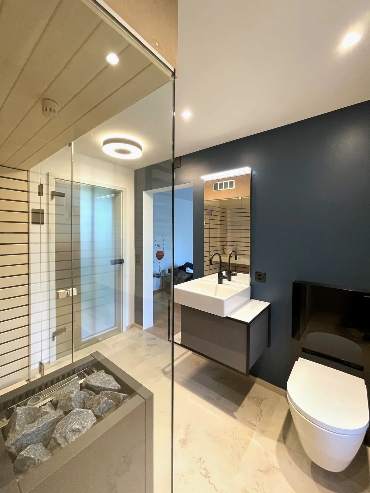 Blick durch die Sauna auf Waschplatz und Wand in Petrol